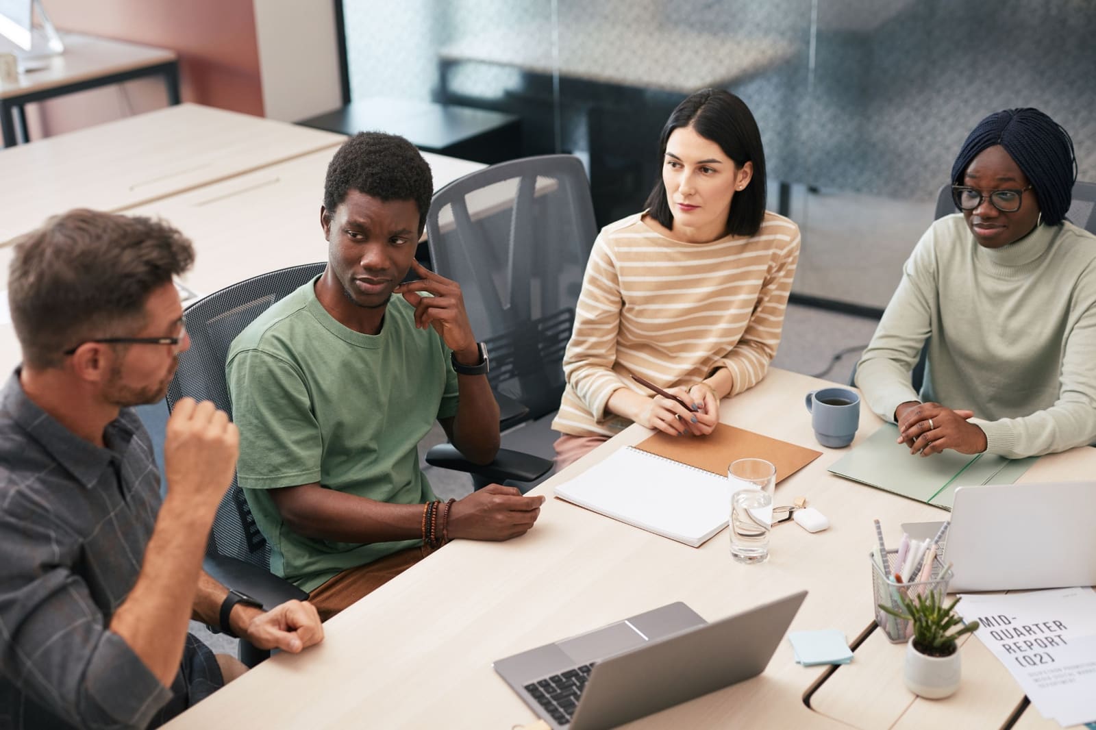 A group listening to a colleague at a meeting table.